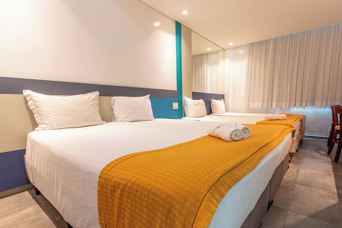 A hotel room with two beds, a large mirror, and a view of the city.