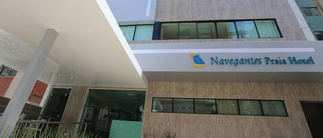 Un edificio moderno di un hotel con un cartello che riporta la scritta "Navegantes Praia Hotel".