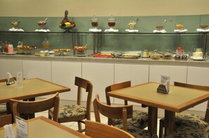 Un espace buffet proposant divers plats et une zone réservée aux repas, avec des tables et des chaises en bois.