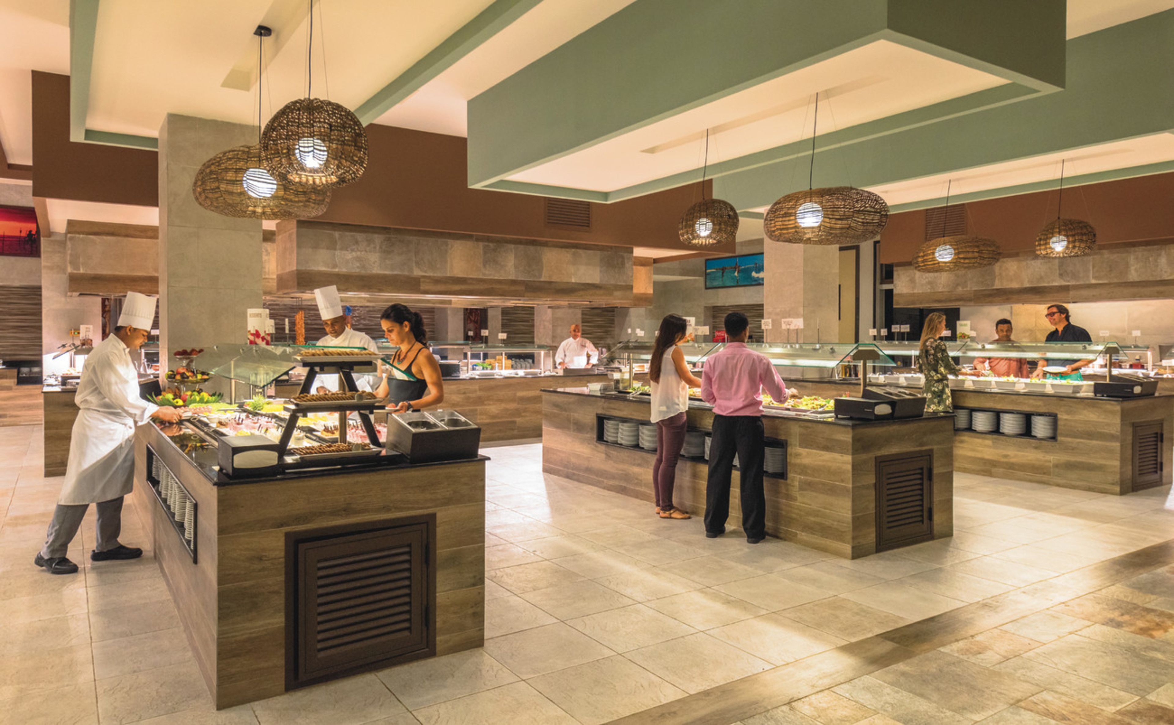 A buffet area with multiple food stations, chefs serving, and a modern interior design.