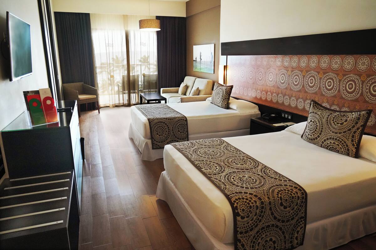 A hotel room with two beds, a TV, a desk, and a chair.
