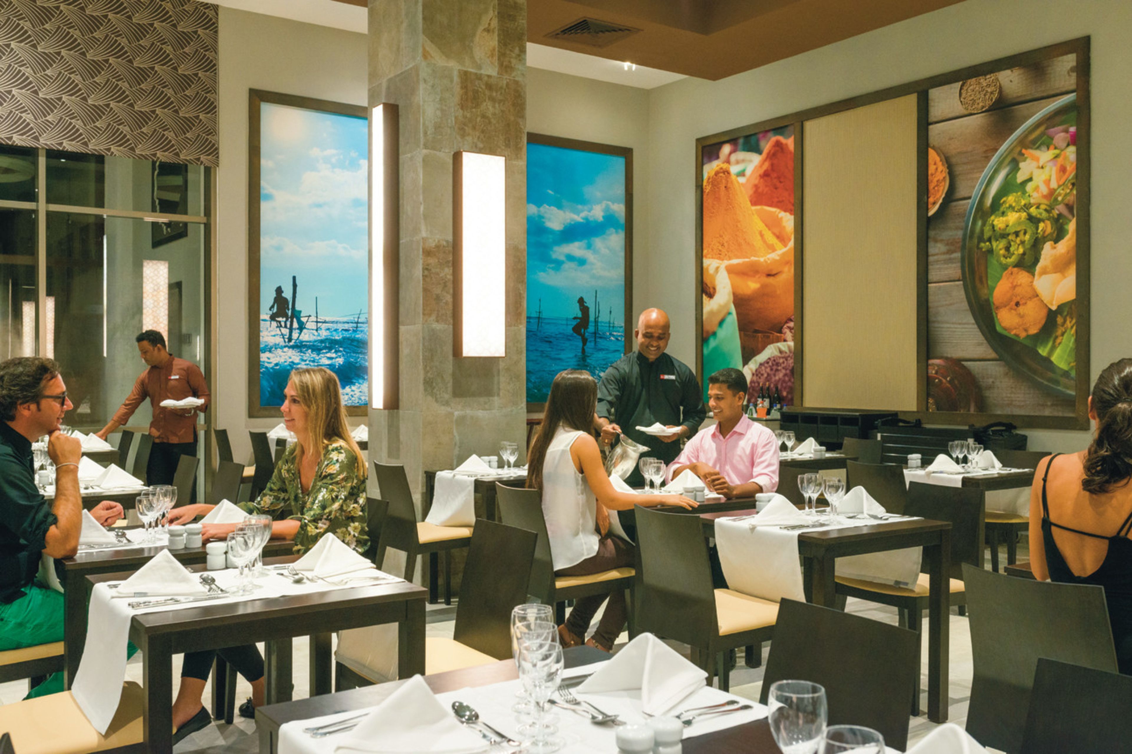 Un restaurante con varias mesas, sillas y comensales.