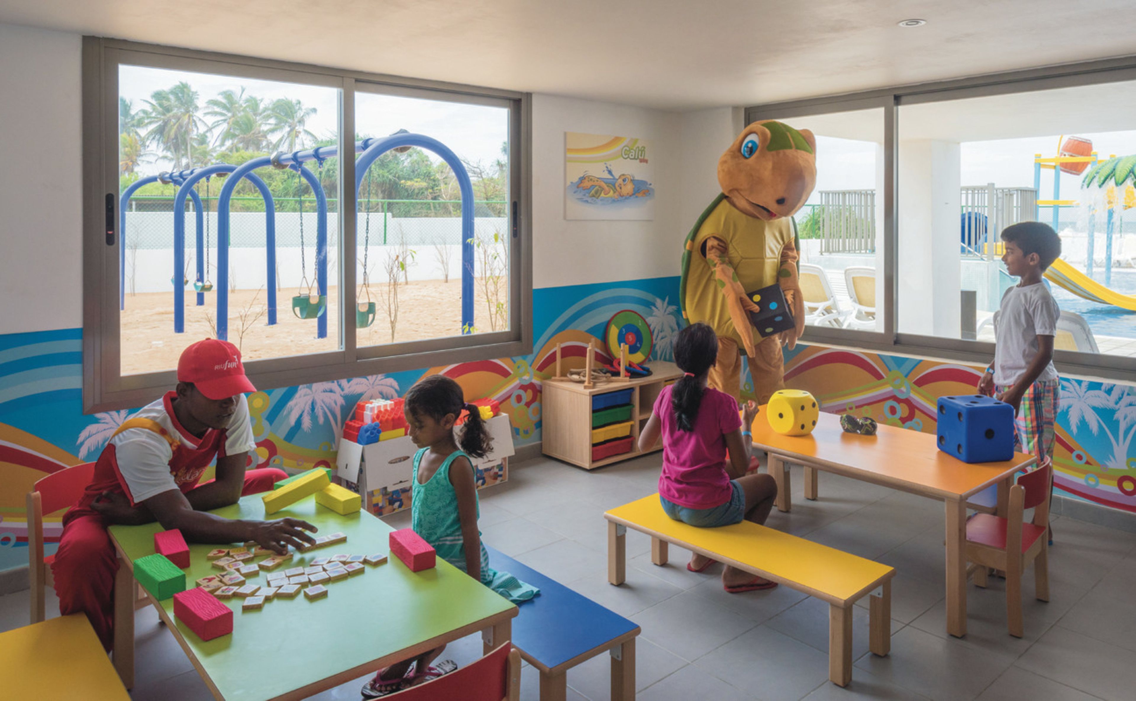 A classroom with children playing and a mascot.