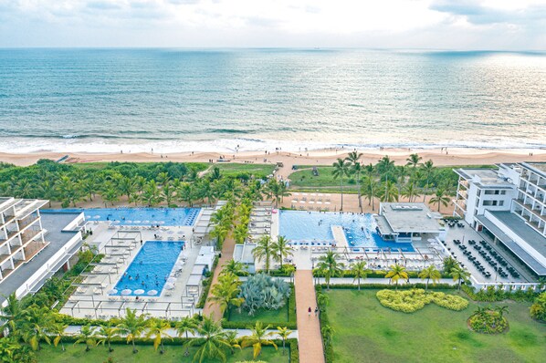 A resort with multiple swimming pools, a beach, and palm trees.