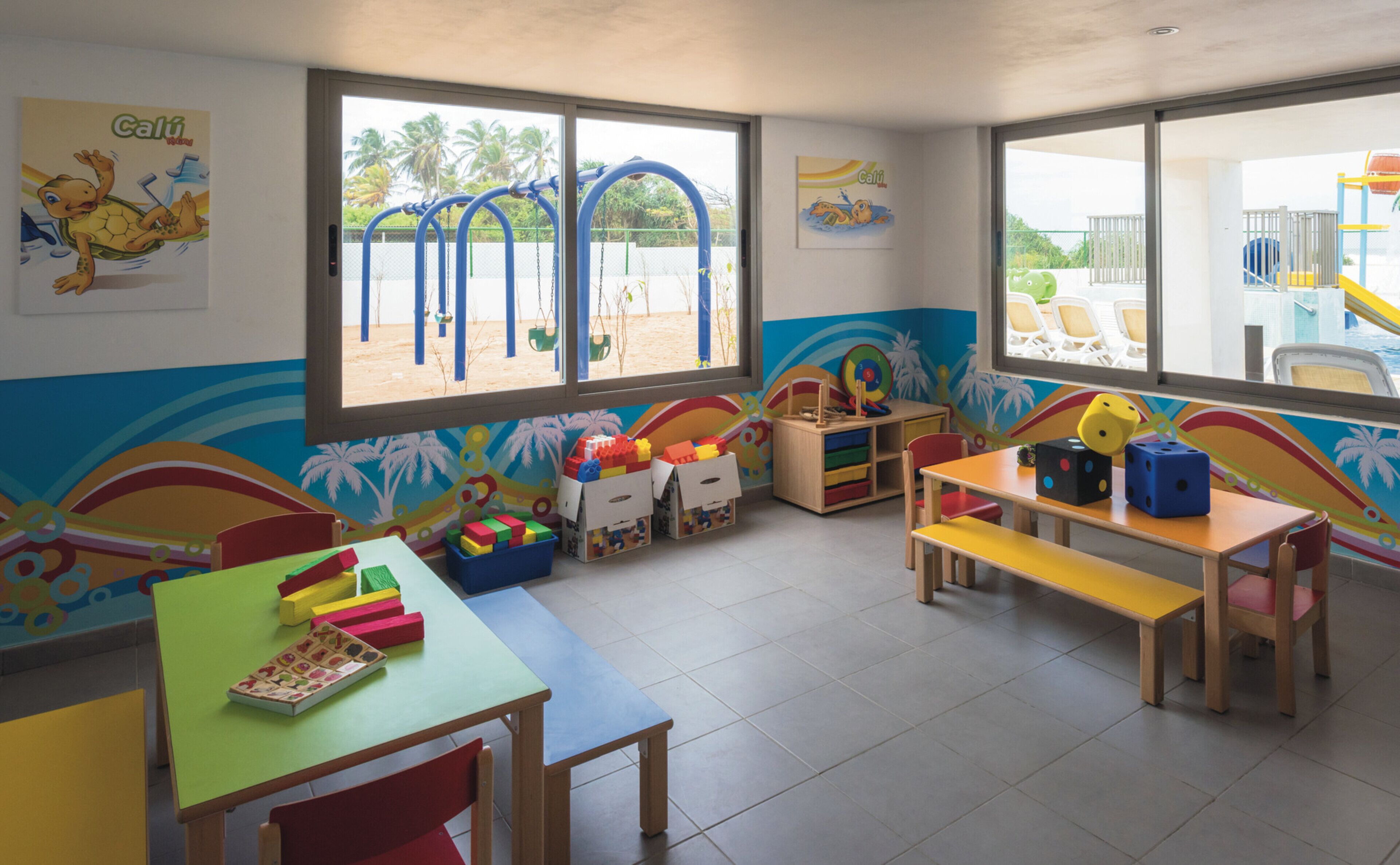A brightly colored children's playroom with a slide, play mats, and various toys.