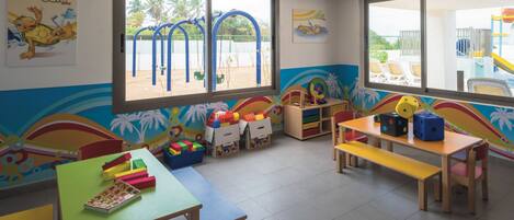 A brightly colored children's playroom with a slide, play mats, and various toys.