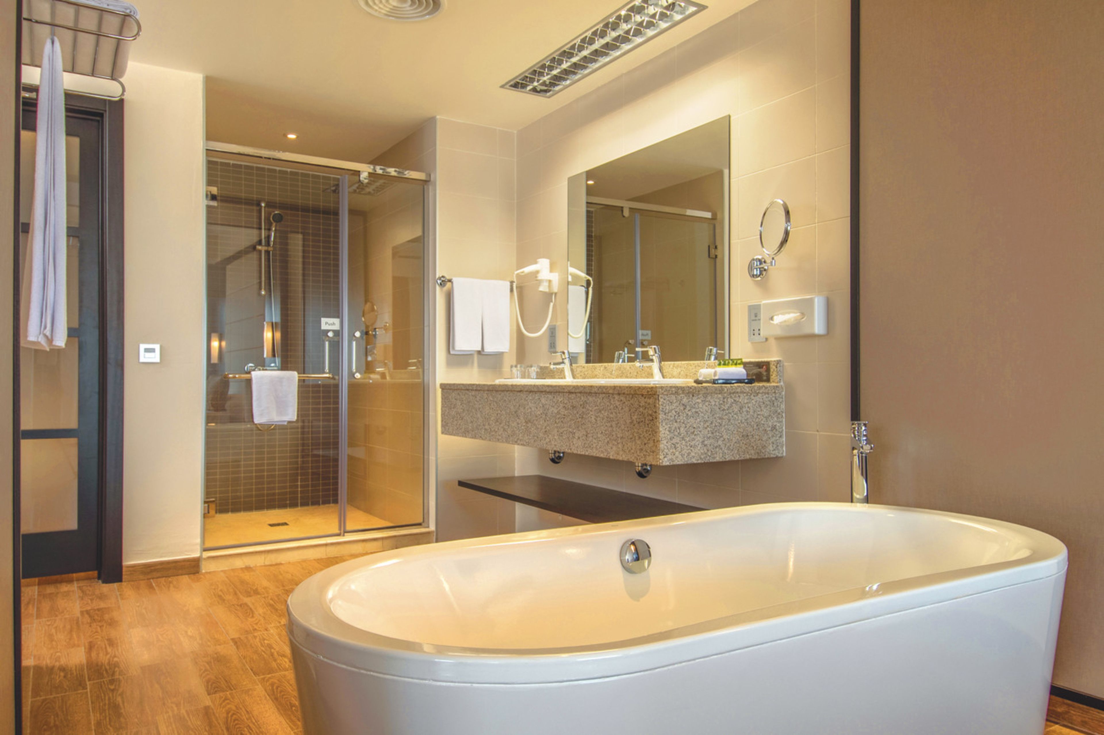 A modern bathroom with a freestanding bathtub, a glass-enclosed shower, and a vanity with a mirror.