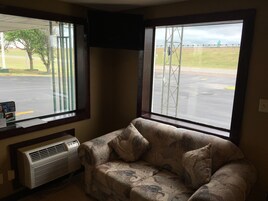 A room with a couch and a window overlooking a parking lot.