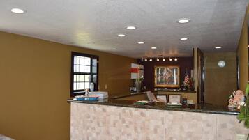 Welcome to our reception area, featuring a warm and inviting atmosphere with a reception desk, framed artwork, and a window with blinds.