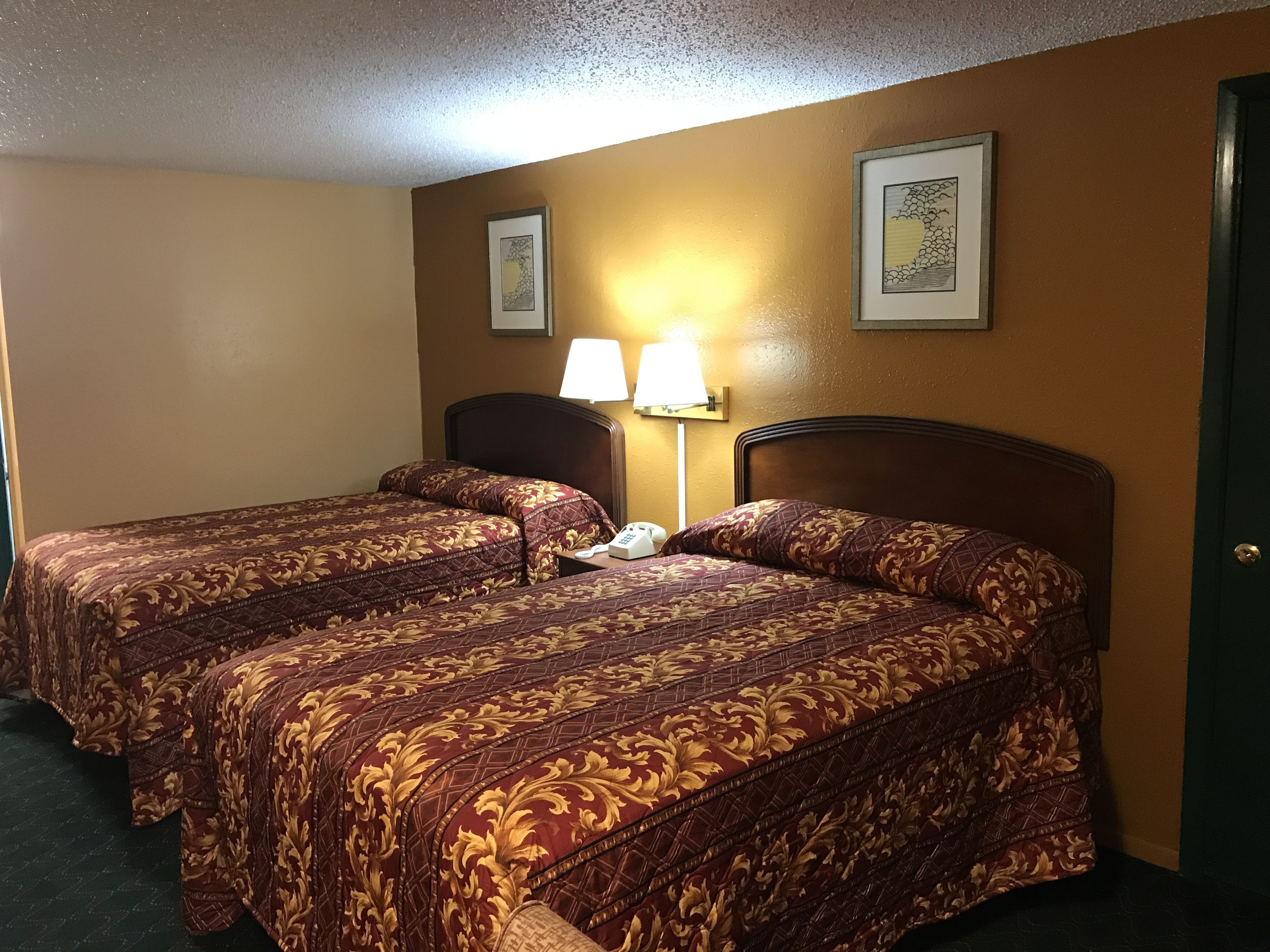 Une chambre d’hôtel avec deux lits, chacun recouvert d’une couvre-lit à motifs, et comprenant une lampe de chevet et un téléphone.