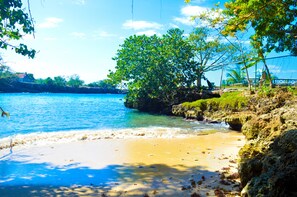A beach with clear water, a sandy shore, and a rocky outcrop with greenery. - Le Mer Guest House & Villa - Lucea (Lucea)