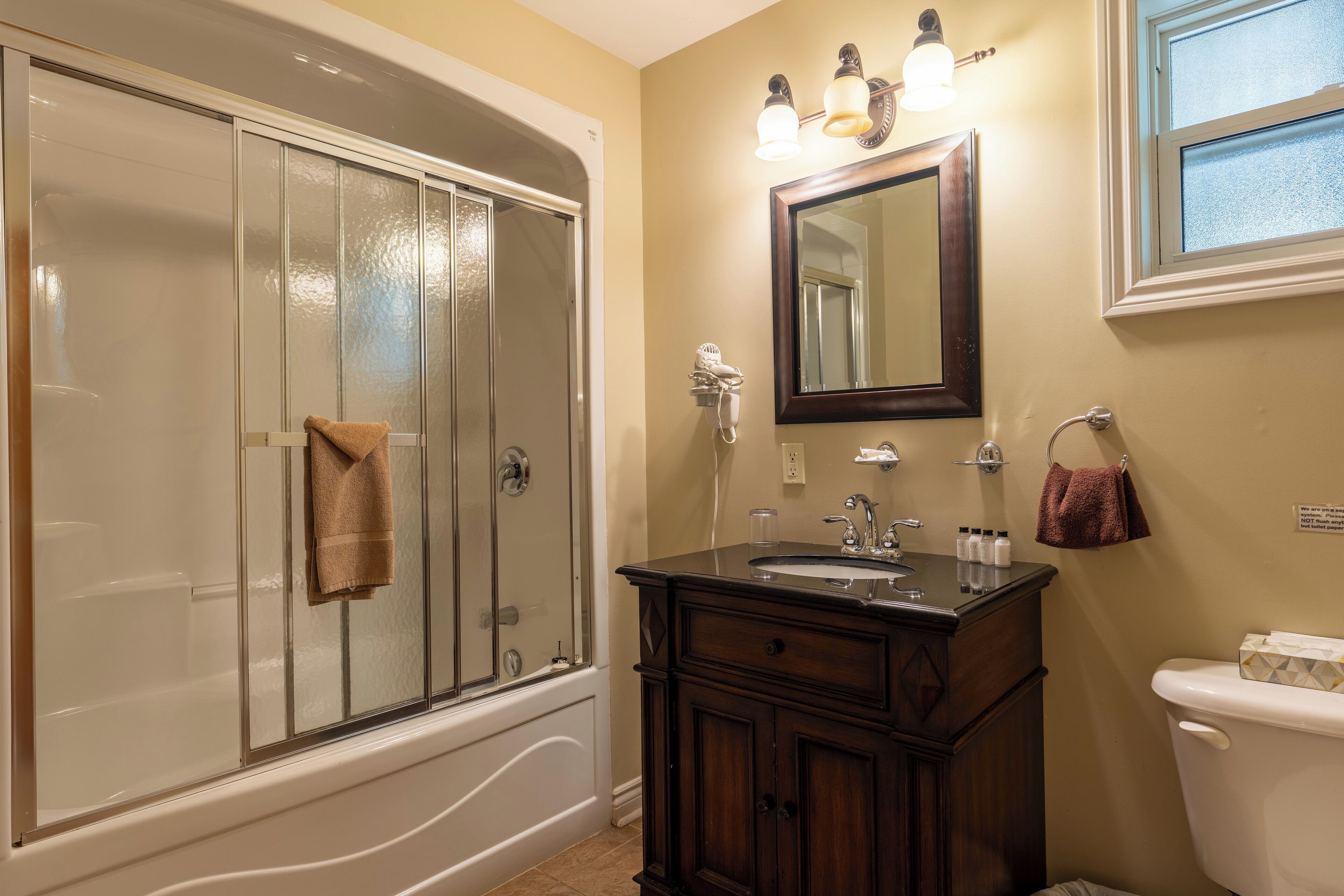 A bathroom with a glass-enclosed shower, a vanity with a sink, and a toilet.