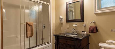 A bathroom with a glass-enclosed shower, a vanity with a sink, and a toilet.