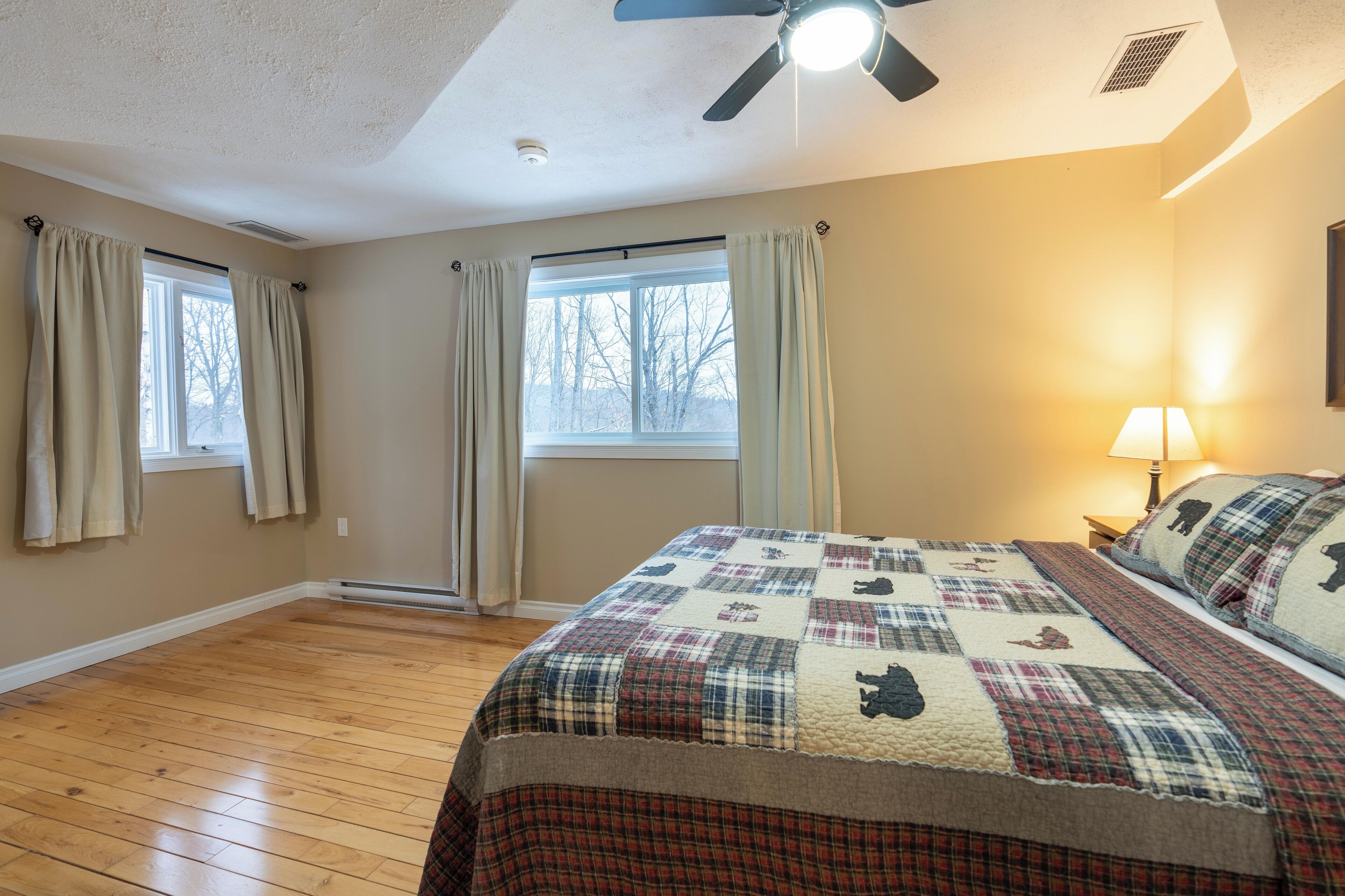 A bedroom with a large bed, a ceiling fan, and a window with curtains.