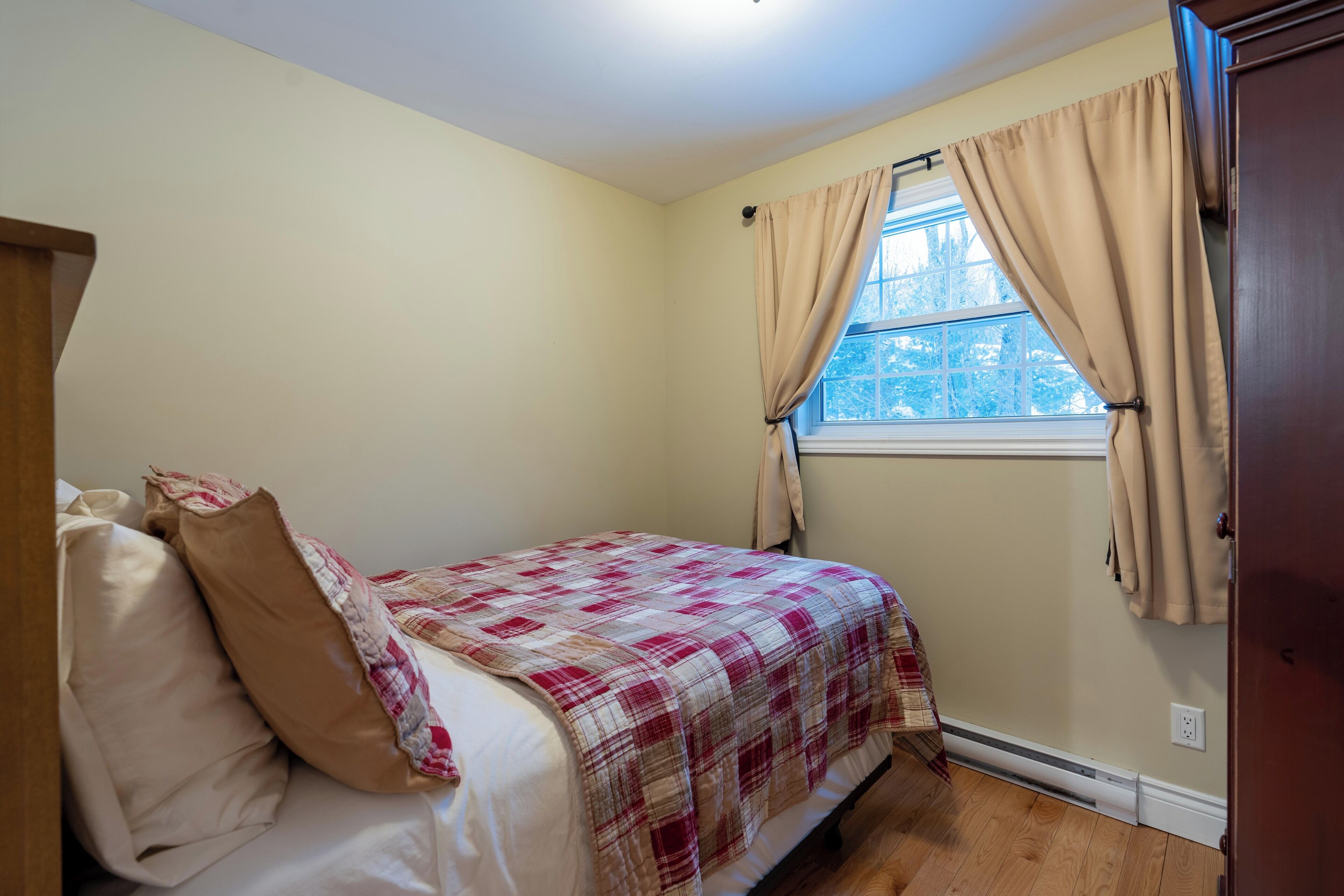 Un dormitorio con una cama, una ventana con cortinas y una puerta de madera.