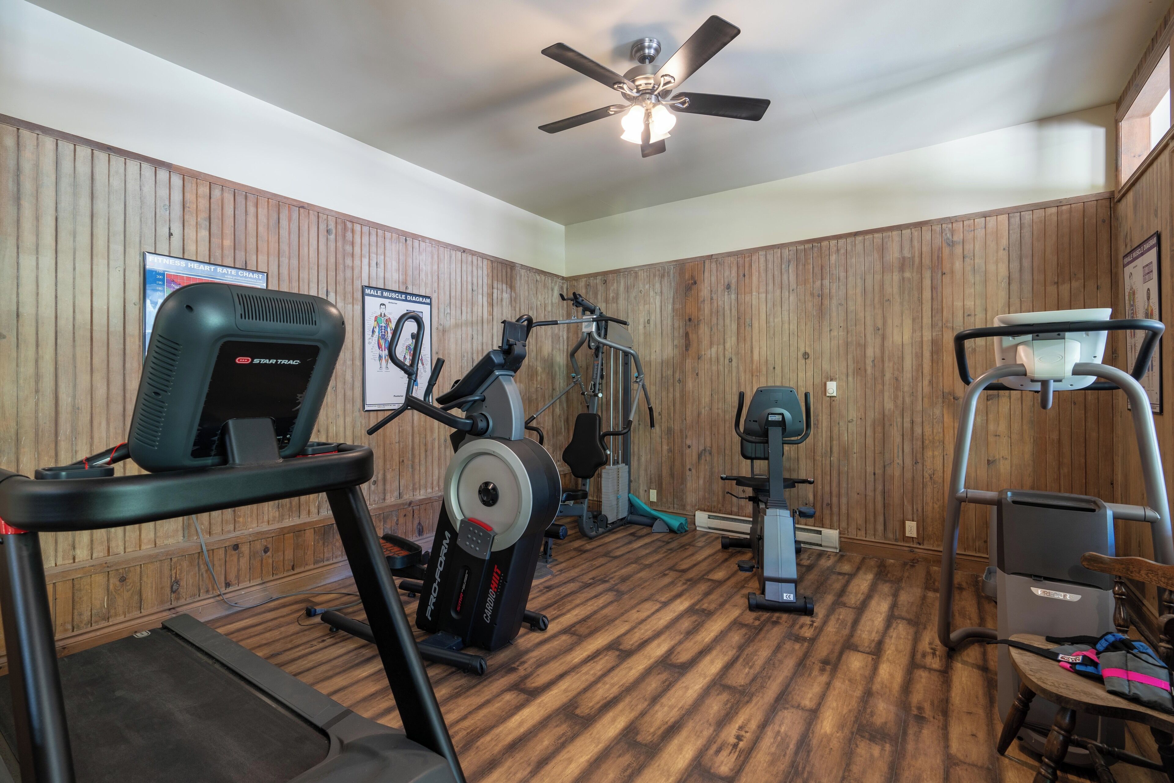 Une salle de sport à domicile équipée d’un tapis de course, d’un vélo d’appartement et d’appareils de musculation.
