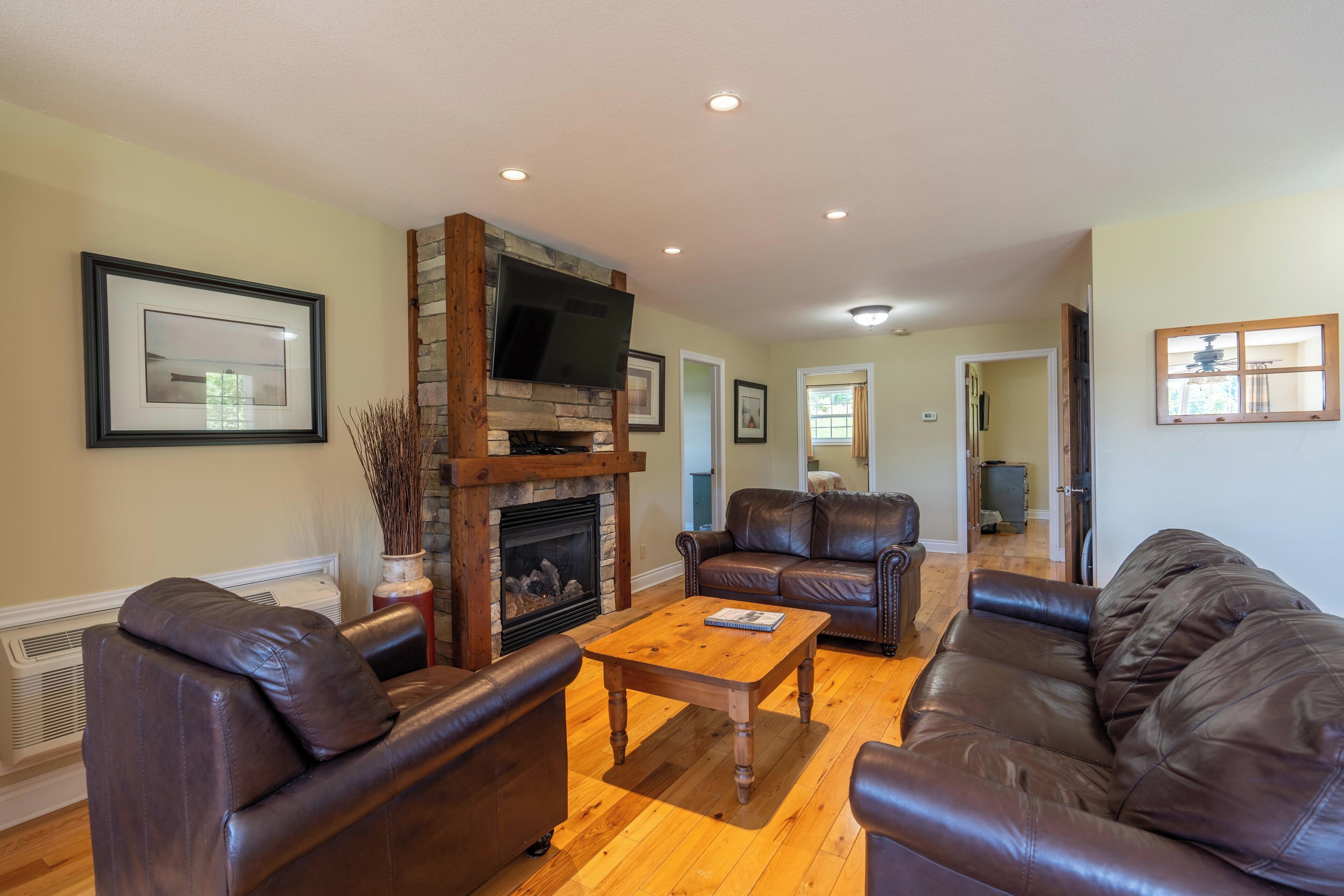 A living room with a fireplace, leather sofas, a wooden coffee table, and a flat-screen TV mounted above the fireplace.