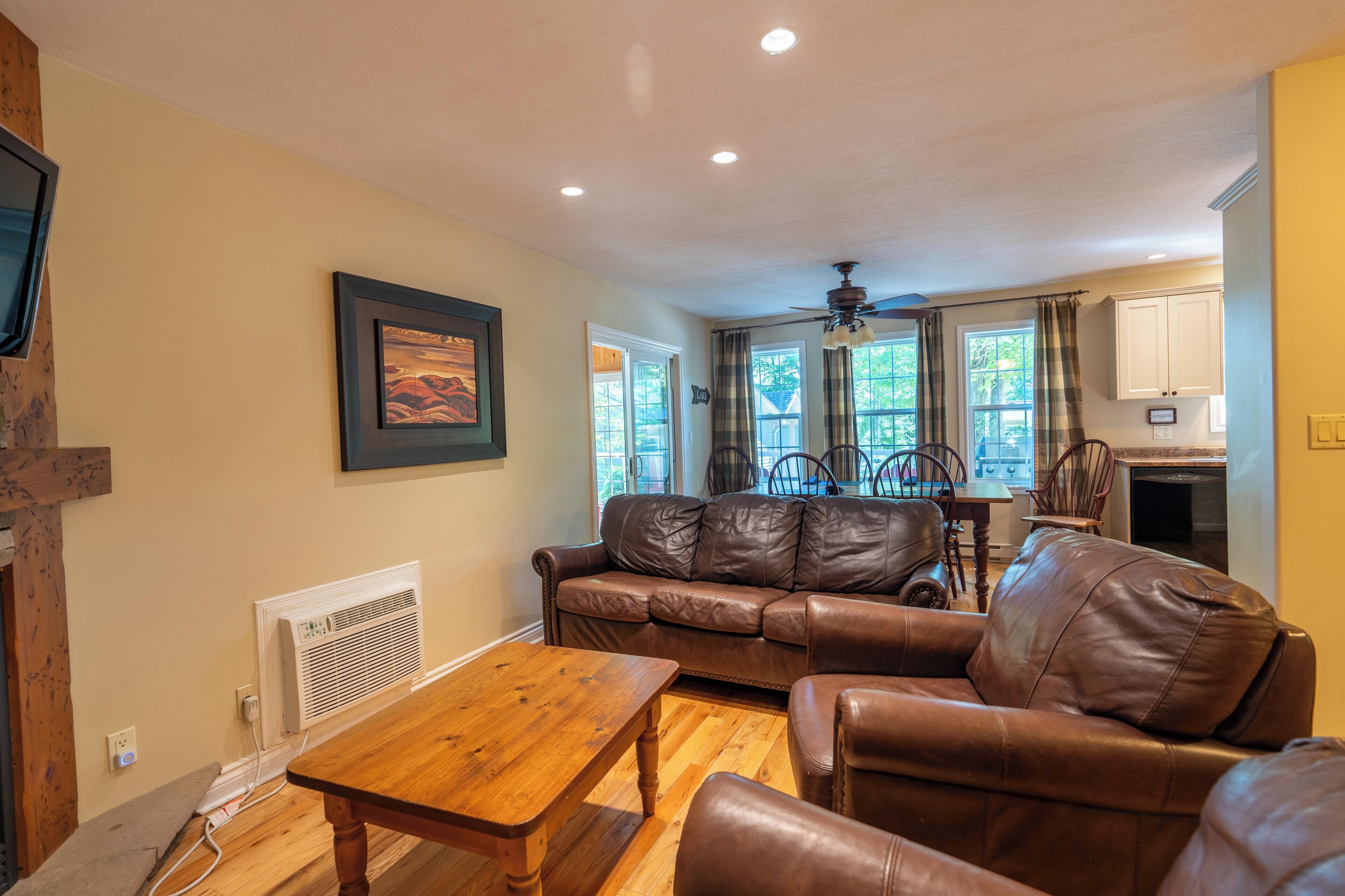 A living room with a brown leather sofa, a wooden coffee table, and a dining area with a table and chairs.