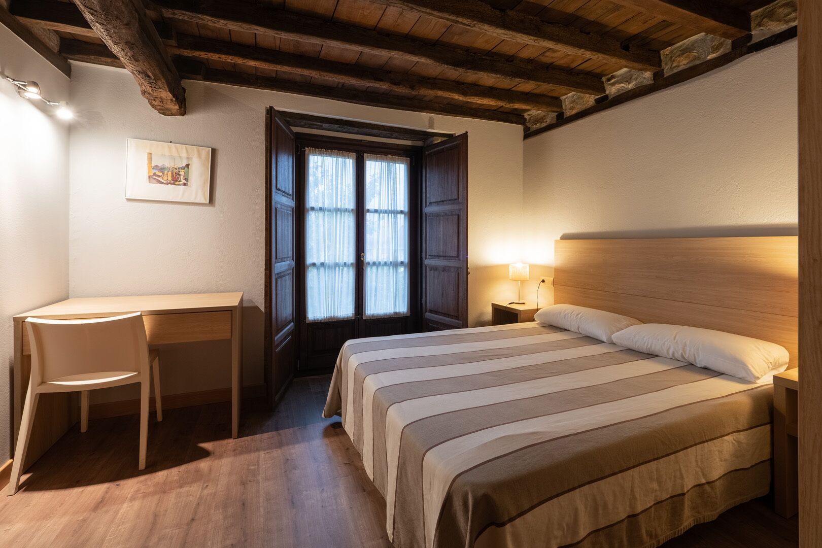 Een slaapkamer met een houten bed, een bureau en een stoel.