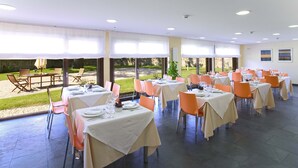 A restaurant with tables set for dining, large windows, and a view of the outdoors. - Apartamentos Posada La Robla (Castaneda)