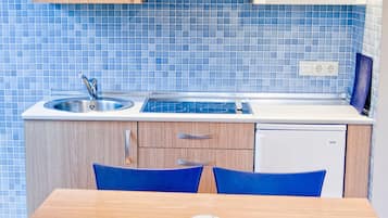 Una cocina con armarios de madera, un microondas, un lavamanos y sillas azules.