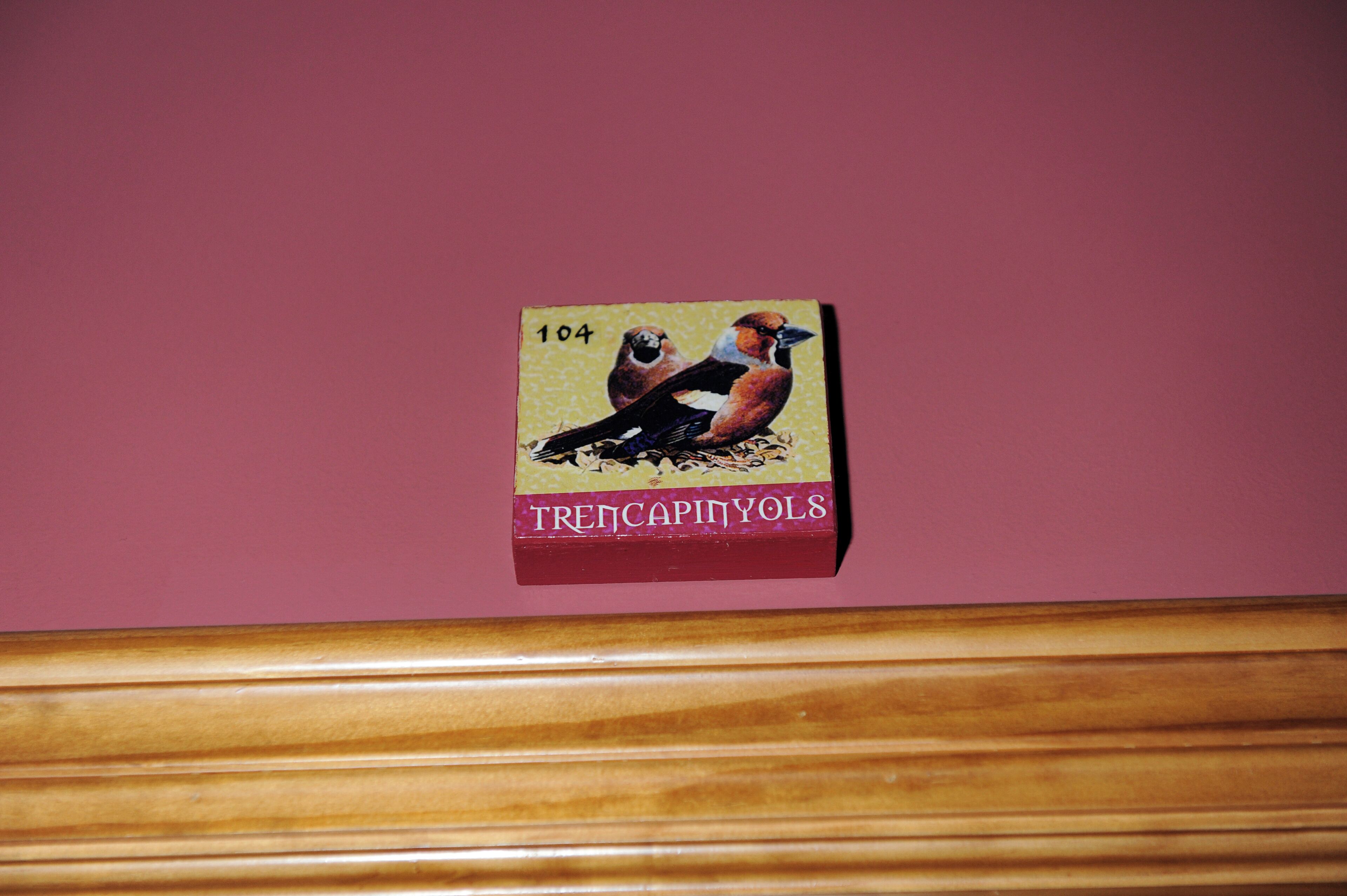 A small, rectangular object with a bird illustration and text on a pink background.