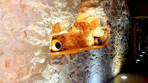 Interior que recuerda a una cueva, con un estante de madera que sostiene dos piezas de cerámica.