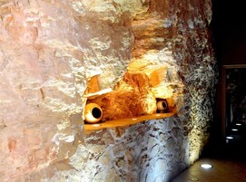 Interior que recuerda a una cueva, con un estante de madera que sostiene dos piezas de cerámica.