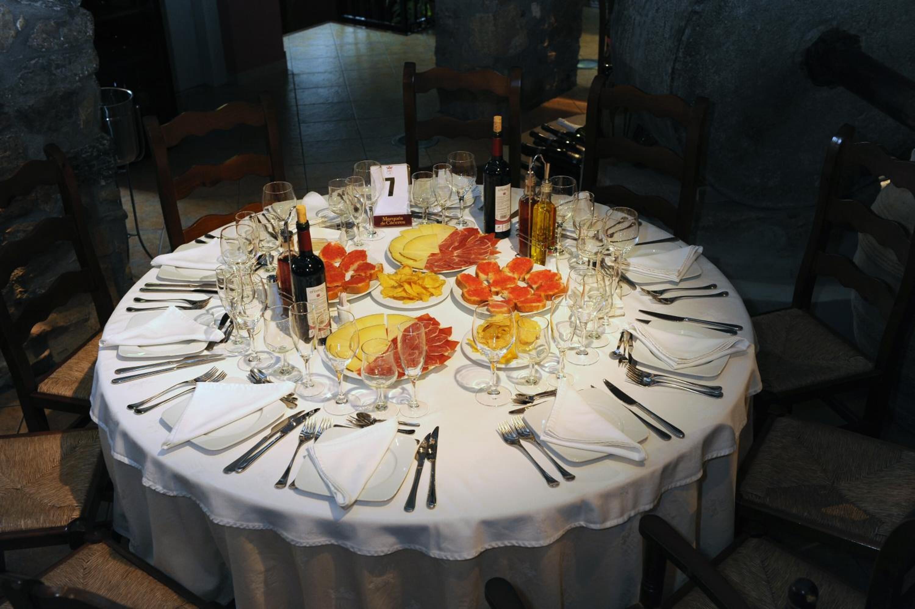 A round dining table set for a meal with plates of food, wine glasses, and cutlery.