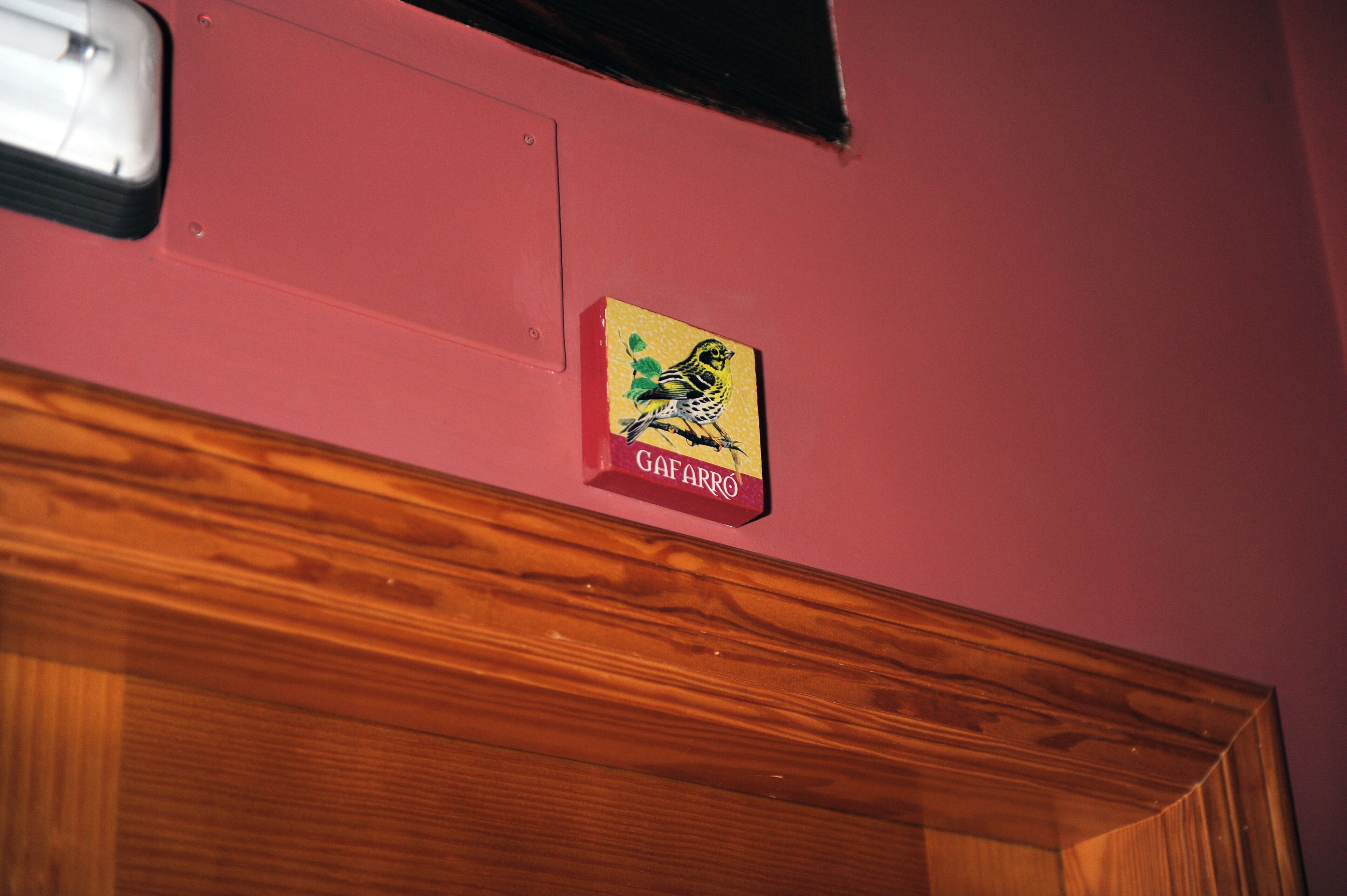 Una puerta de madera con una pared rosa y un letrero pequeño encima.
