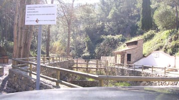 A natural park with stone pathways, wooden fences, and a small stone building.