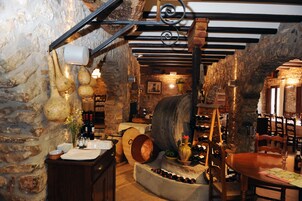 Una bodega rústica con paredes de piedra, barriles de madera y una estantería para vinos.