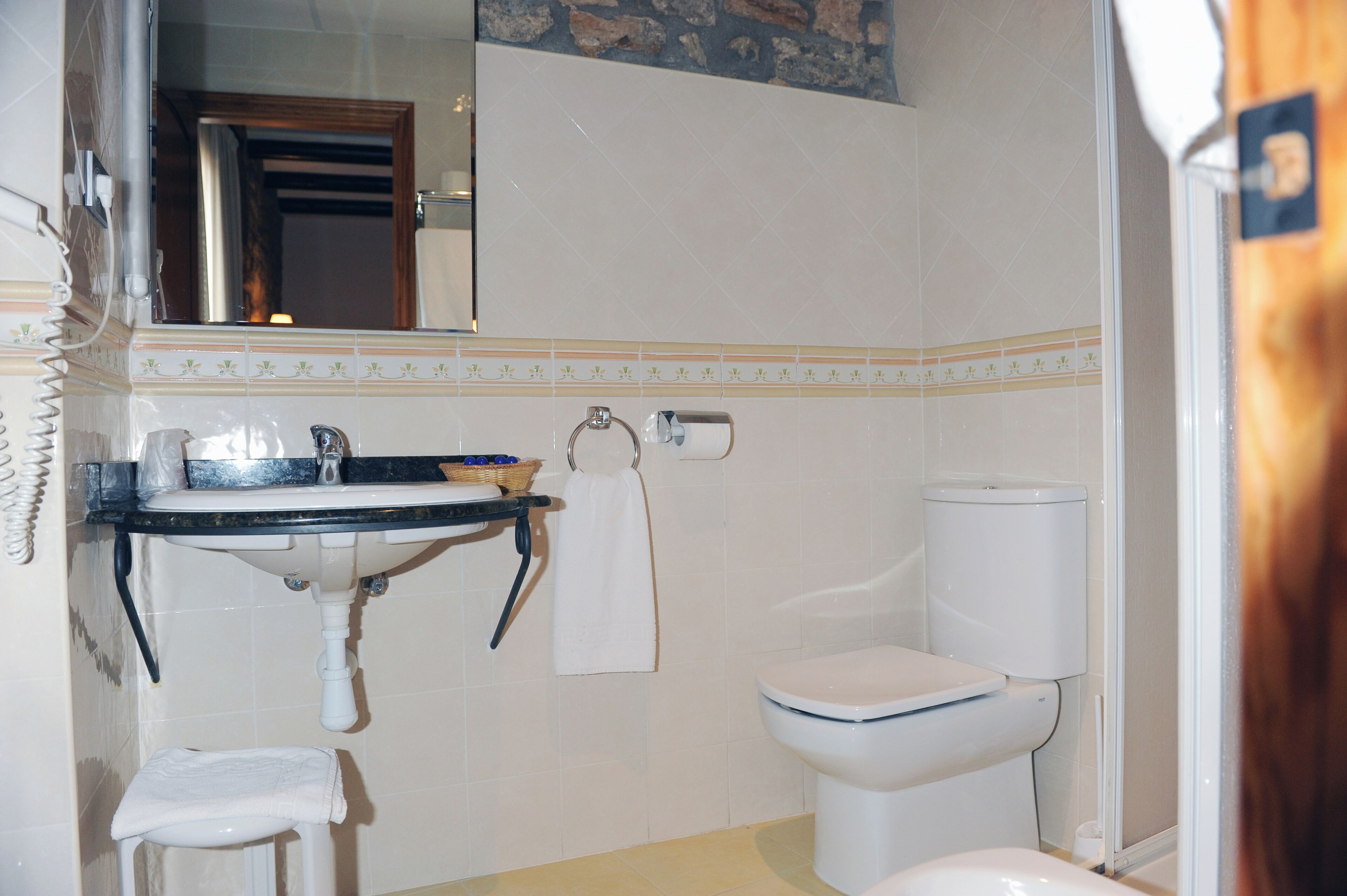 Une salle de bain avec un lavabo, des toilettes et un miroir.