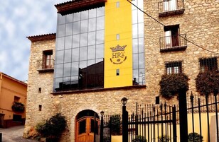 Un edificio de piedra con una franja vertical amarilla y el logotipo de una corona, que indica un hotel o restaurante.