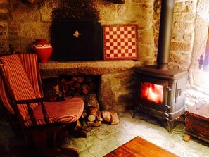 A stone fireplace with a checkered board, a chair, and a red vase. - Casa Grande de Fuentemayor (Silleda)