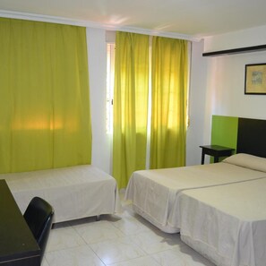 A hotel room with two beds, a desk, and a small table.