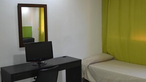 Une pièce comprenant un bureau, une chaise, un lit et un miroir au mur.