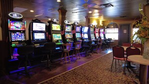 Eine Reihe Spielautomaten in einem Casino mit Teppichboden und Holzsesseln.