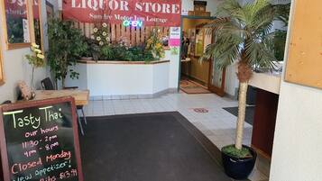 Interior de un restaurante con un letrero de licorería, un menú en la pizarra y una palmera.