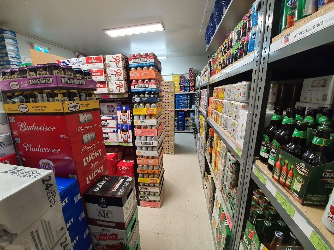 A grocery store aisle with various beer brands and other beverages.