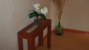 A wooden console table with a vase of white flowers and pampas grass. - Hotel Canabal (Burela)