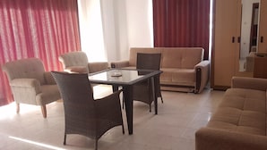 A living room with a sofa, armchairs, and a glass-top table. - Carmen Suite Hotel (Alanya)
