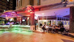 An outdoor bar area with a counter, seating, and a view of the building's interior. - Carmen Suite Hotel (Alanya)
