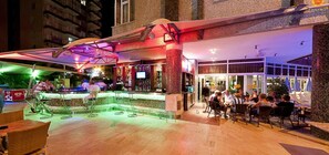 Un área de bar al aire libre con mostrador, asientos y vistas al interior del edificio.