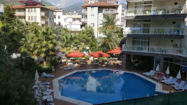 A hotel with a swimming pool surrounded by palm trees and lounge chairs.