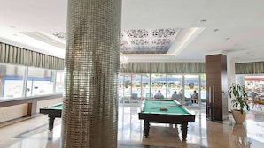 A pool table in a well-lit indoor area with large windows and a decorative ceiling. - Carmen Suite Hotel (Alanya)
