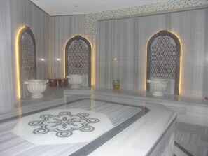 A bathroom with a marble floor, three arched windows with patterned glass, and a central decorative tile. - Carmen Suite Hotel (Alanya)
