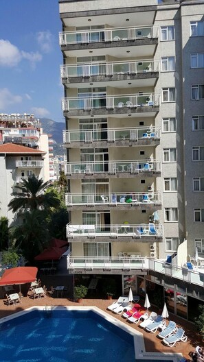 A multi-story hotel with balconies, a swimming pool, and outdoor seating. - Carmen Suite Hotel (Alanya)