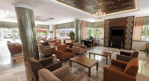 A spacious lobby with a chandelier, comfortable seating, and large windows.