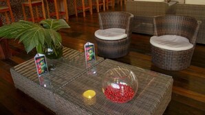 A lobby with wicker furniture, a glass coffee table, and a potted plant. - Heliconia Amazon River Lodge (Indiana)